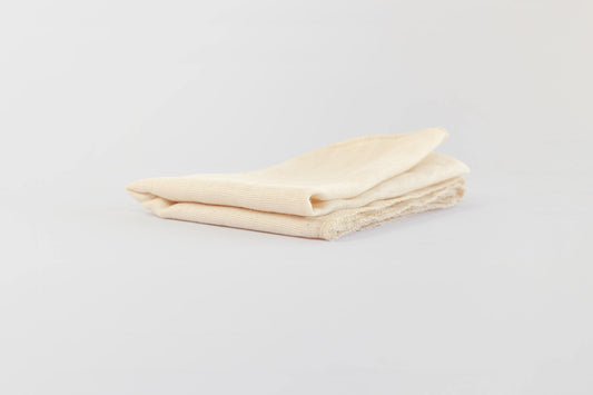 Close up of folded, hemmed natural, food-safe muslin cloth for soy milk straining and tofu making on a white background.