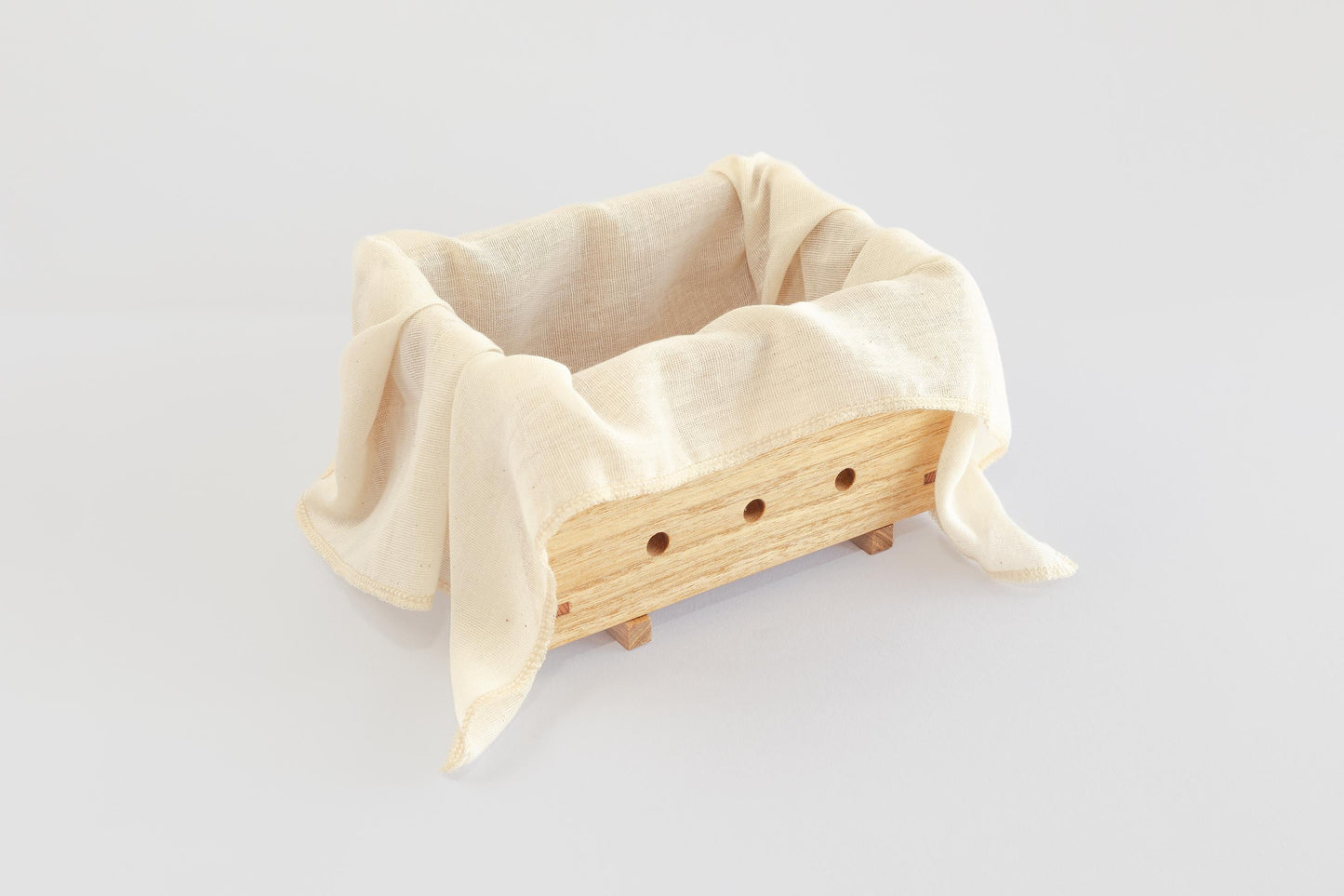 A wooden tofu press made by Tofu Press Australia lined with natural muslin cloth on a white background. Front angled view.