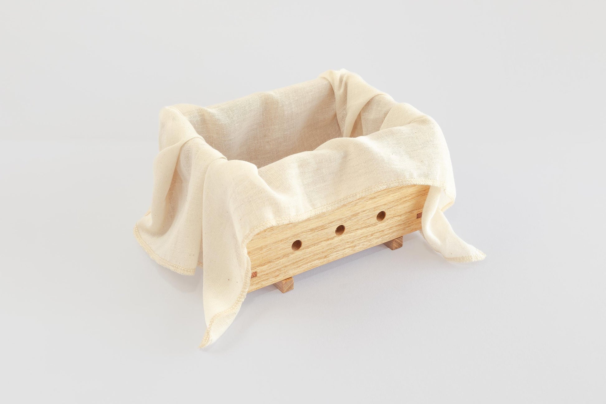 A wooden tofu press made by Tofu Press Australia lined with natural muslin cloth on a white background. Front angled view.