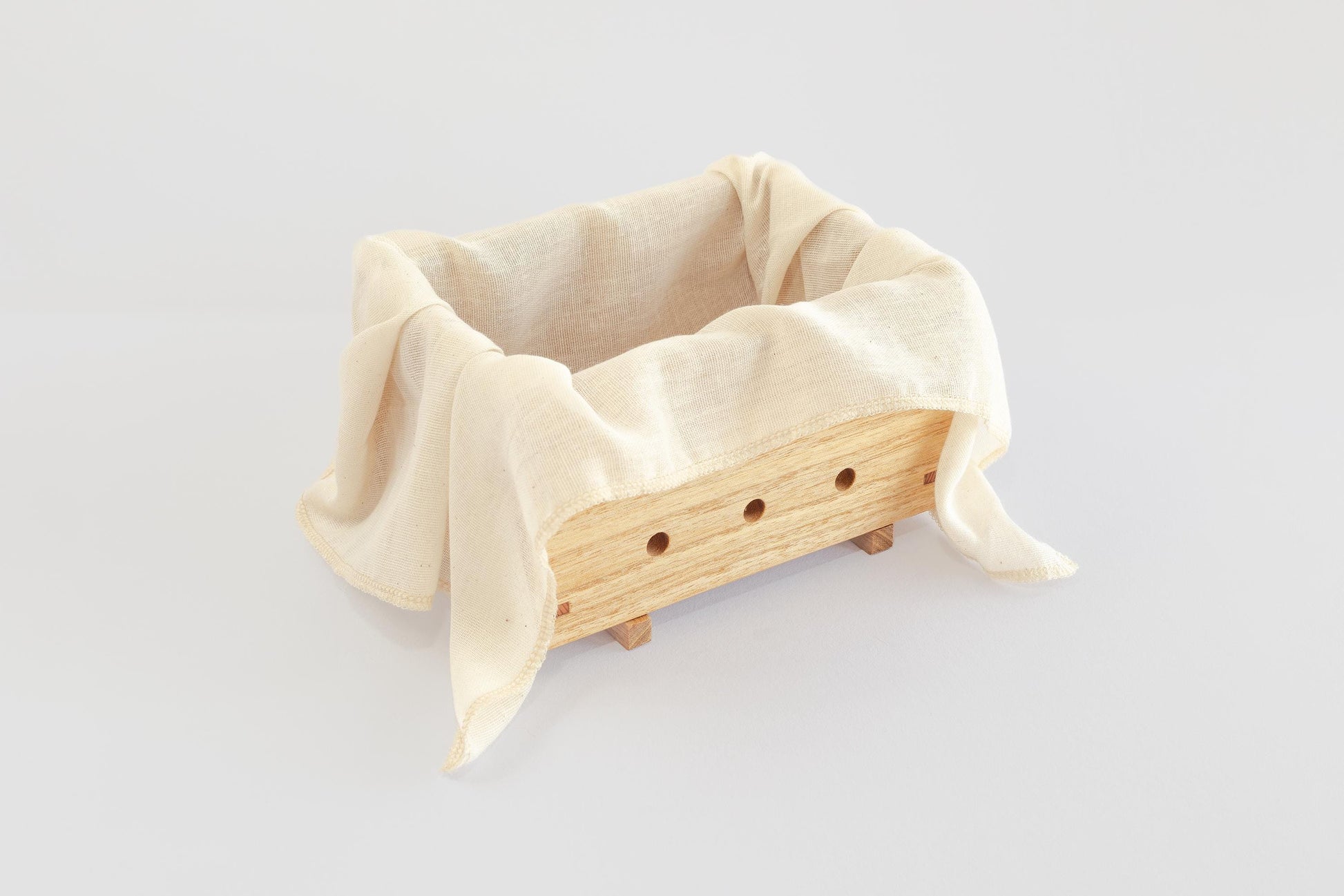 Product image of a wooden tofu press (by Tofu Press Australia) lined with muslin cloth on a white background.
