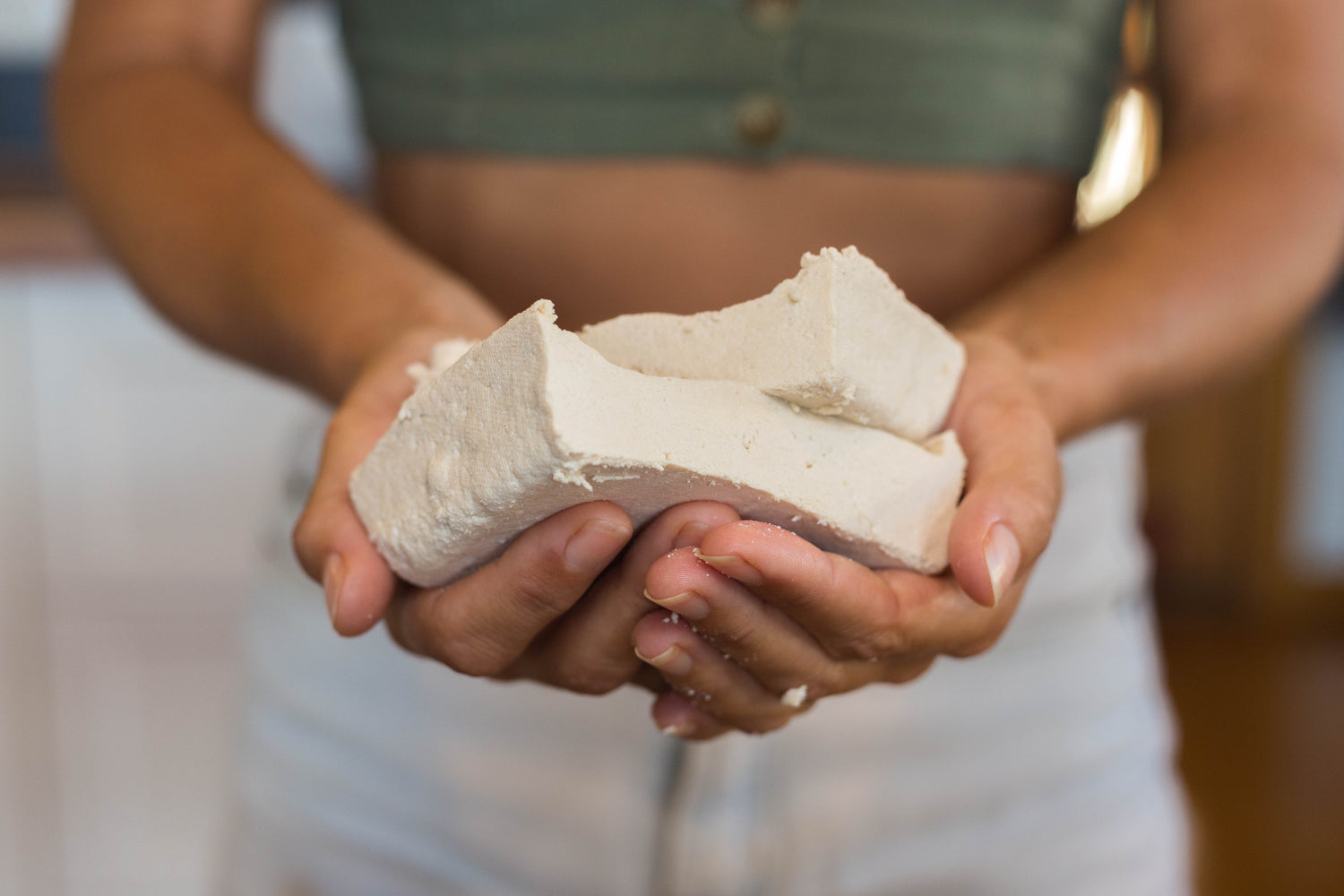 Close up of woman's hands holding home made tofu.