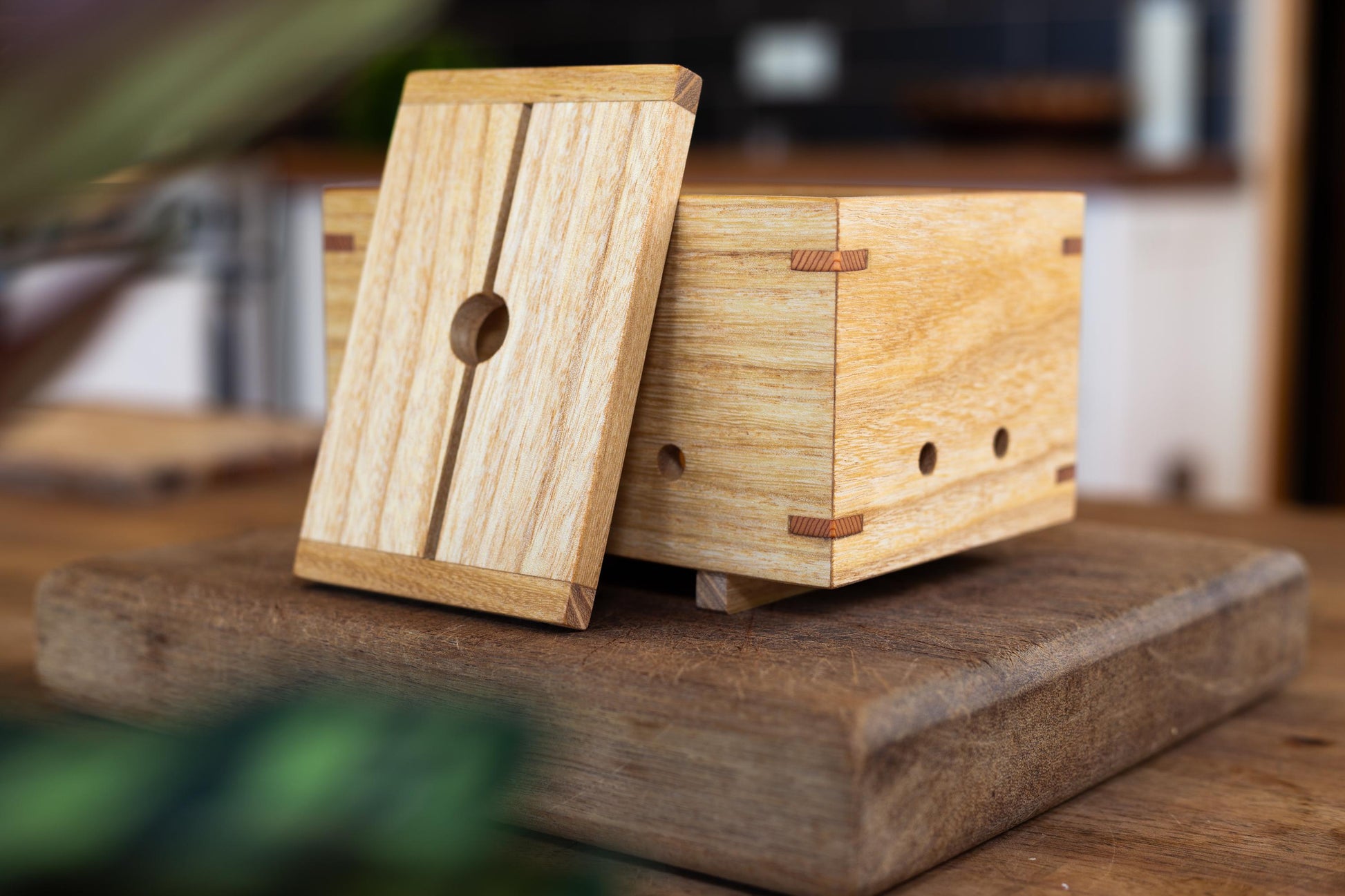 Artistic shot of an elegant, handcrafted wooden tofu press by Tofu Press Australia on a rustic wooden bench and kitchen setting.