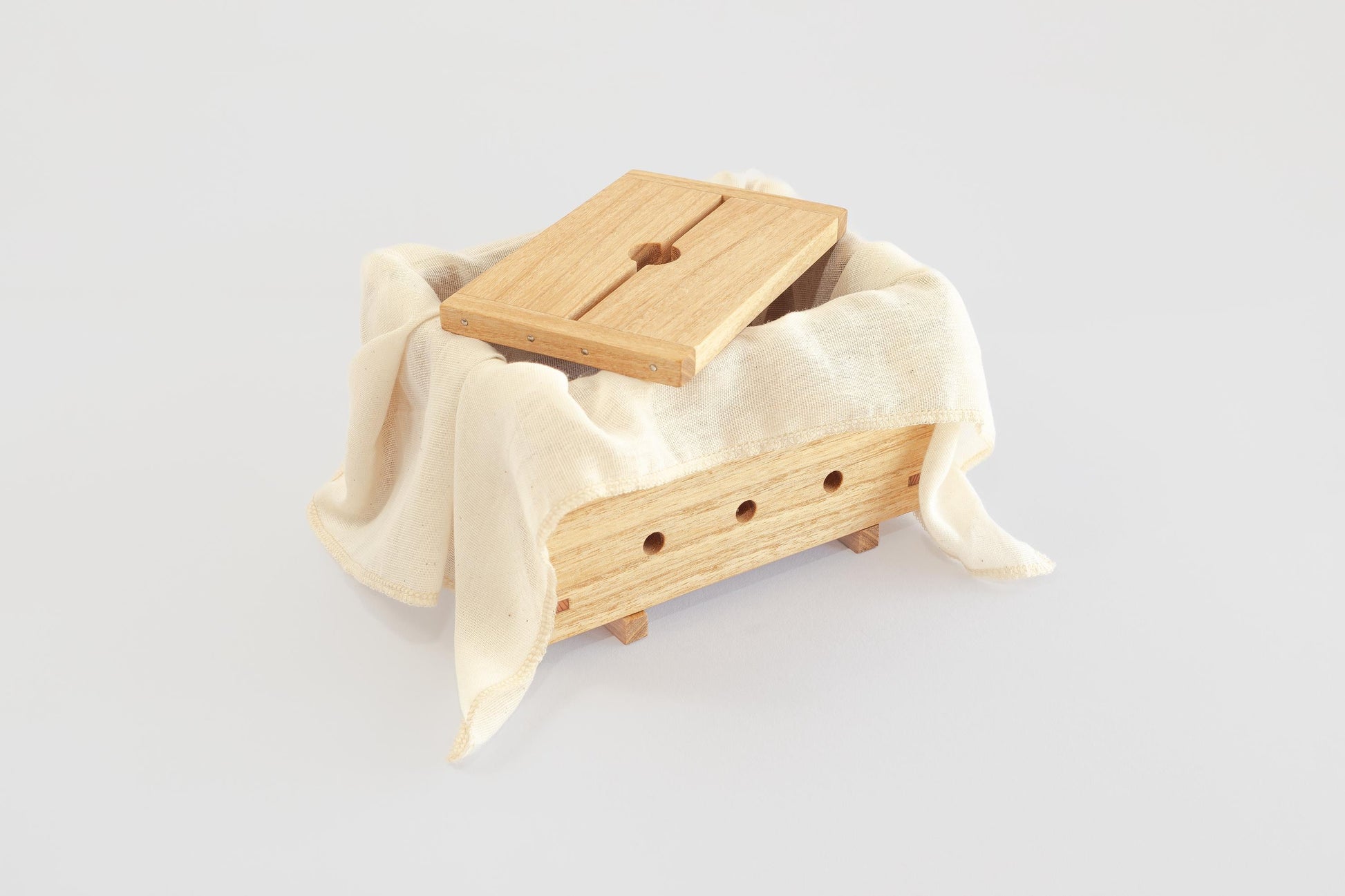 Product image of a wooden tofu press (by Tofu Press Australia) and lid, lined with muslin cloth on a white background.